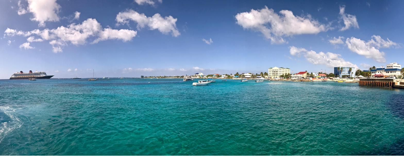 George Town harbour on Grand Cayman with the waterfront, moored boats and a cruise ship under a bright sky